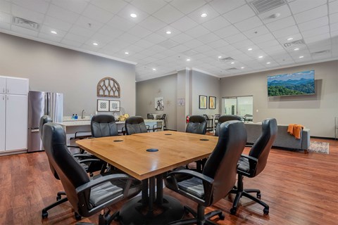 A conference room with a large table surrounded by chairs.