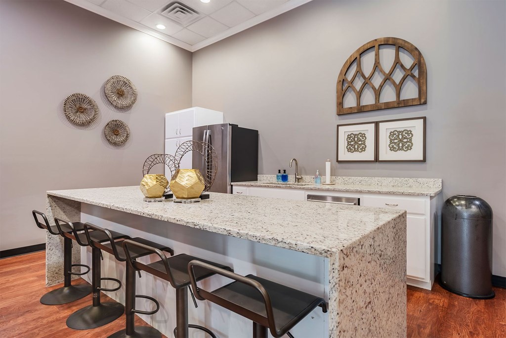 A kitchen with a granite countertop and bar stools.