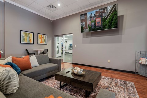 A living room with a grey couch, a coffee table, and a painting on the wall.