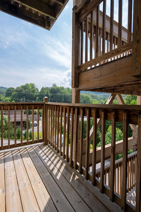 A wooden balcony with a view of the trees.