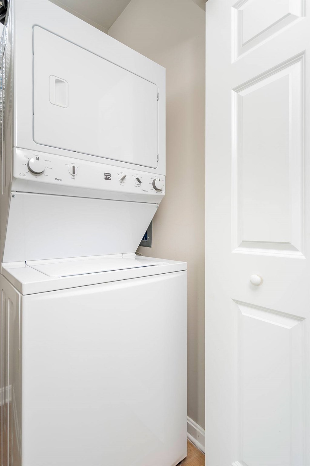 A white dryer is sitting next to a white door.