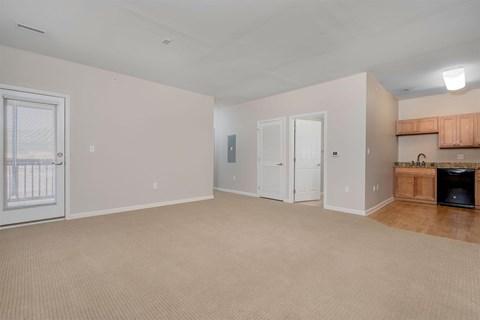 A room with a carpeted floor and a door on the left side.