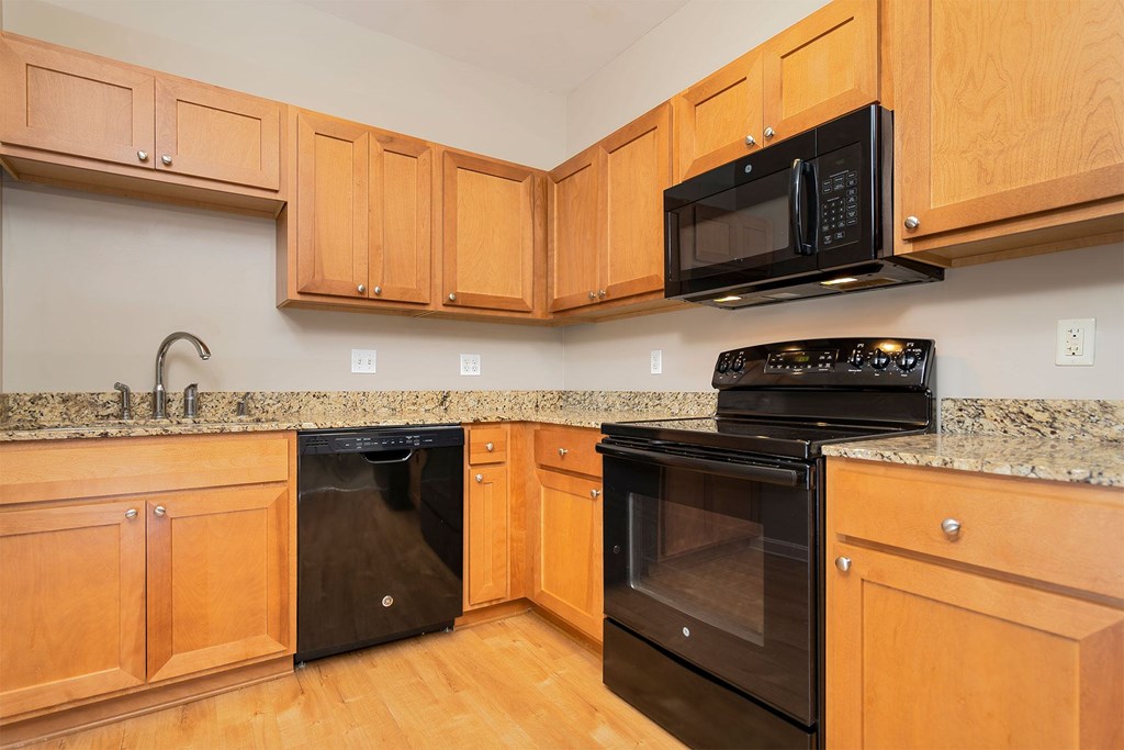 A kitchen with wooden cabinets and black appliances.