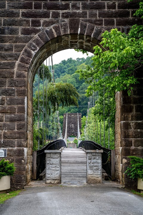 A stone archway with a gate in front of a lush green hillside.