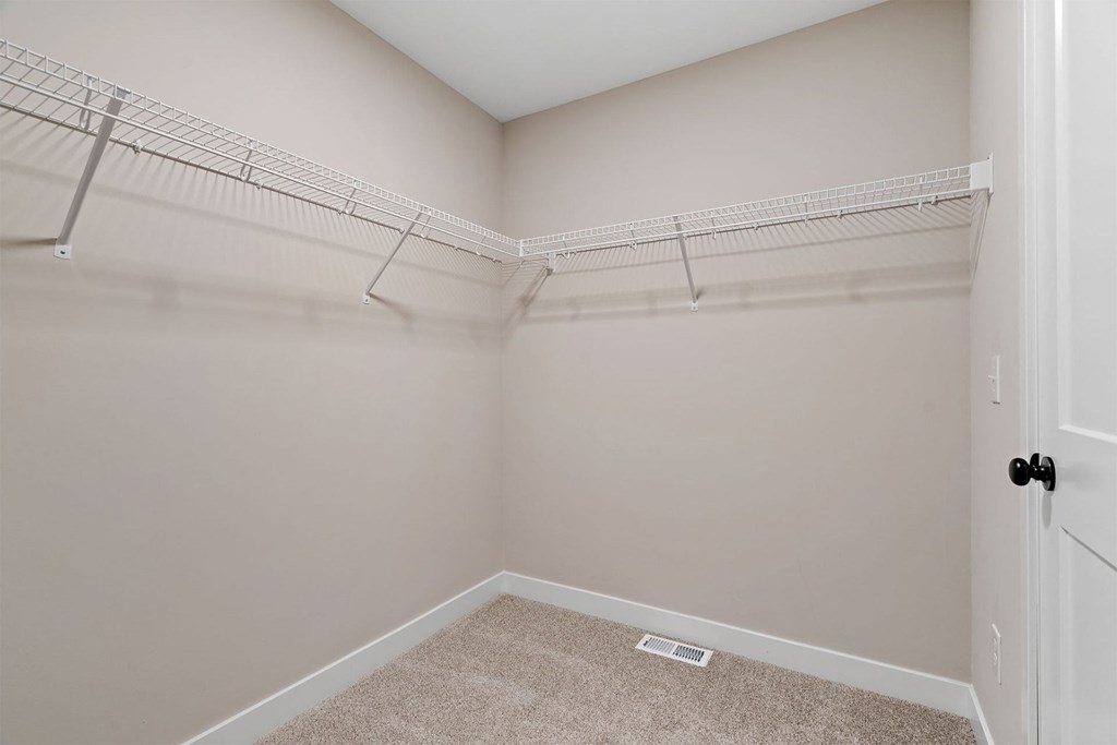 the closet in a bedroom with a mirrored door and shelves on the wall