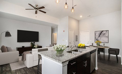 A modern kitchen with a large island and a living room area with a couch and a television.
