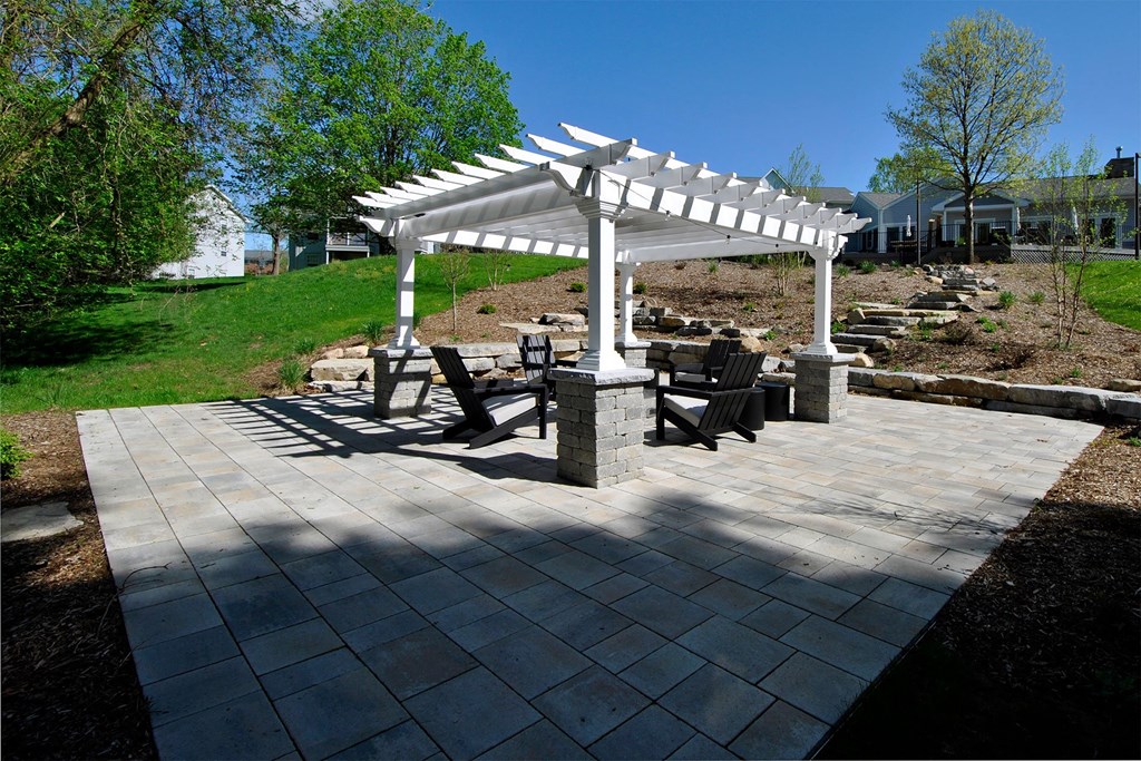 a stone patio with a white pavilion and benches