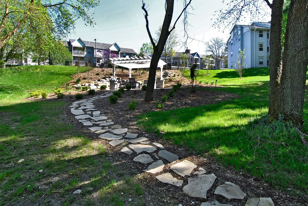 a stone path leading to a park with houses in the background