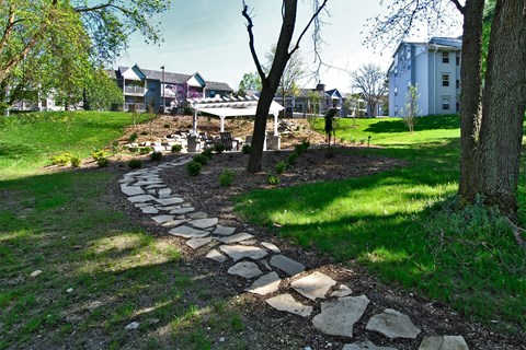 a stone path leading to a park with houses in the background