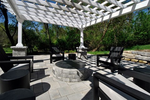 a covered patio with a fire pit and chairs
