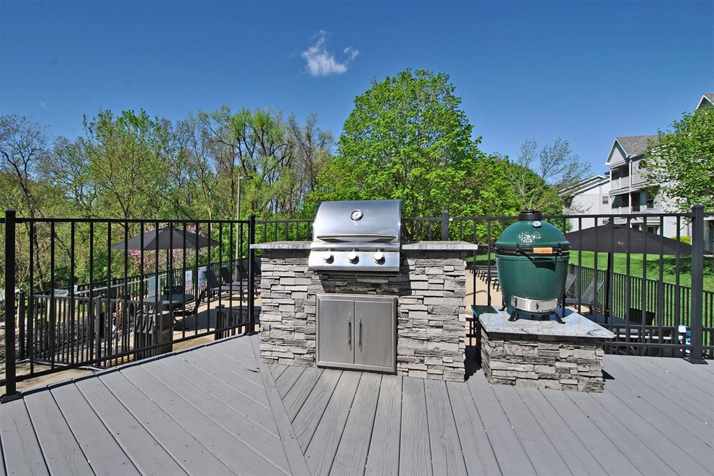 the deck has a grill and a table with a green trash can