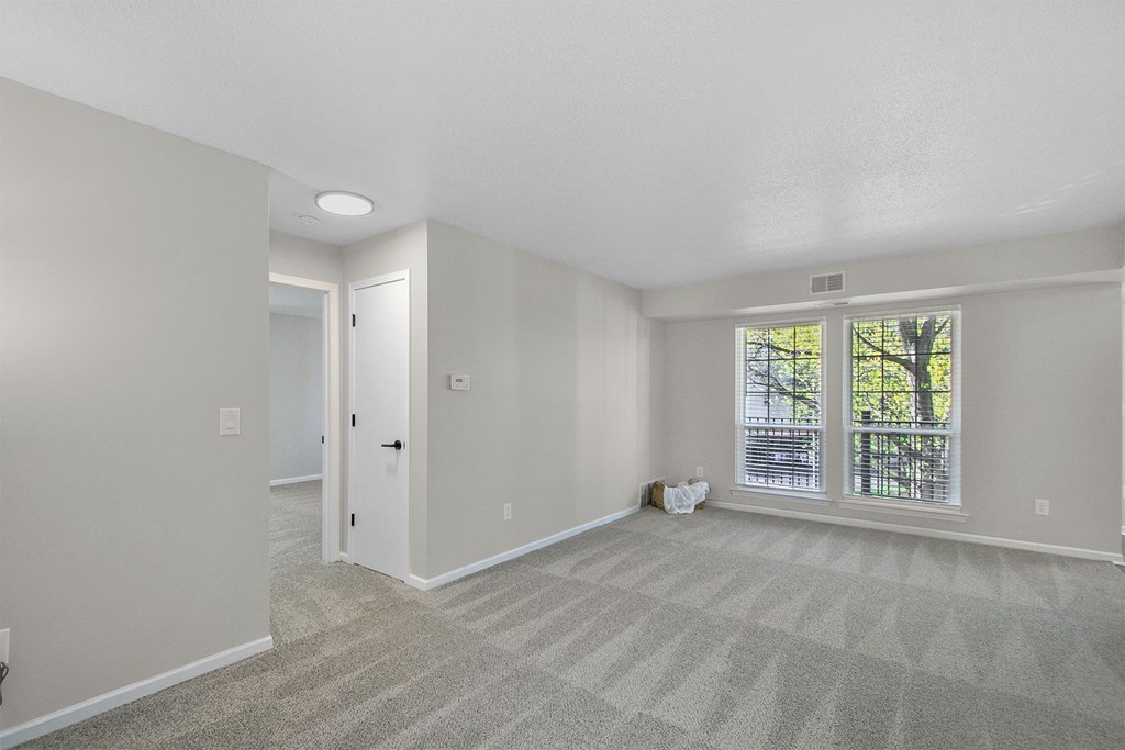 an empty living room with a large window and carpeting
