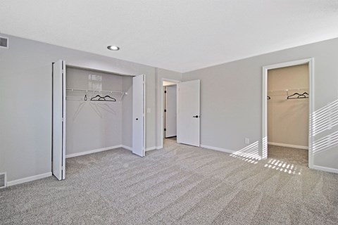 an empty bedroom with mirrored closet doors and carpeting