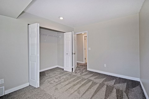 an empty bedroom with a closet and a mirrored closet door