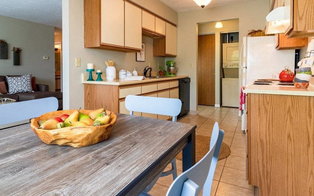 a kitchen and dining room with a bowl of fruit on a table