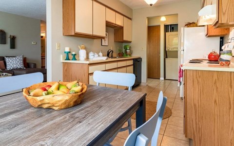 a kitchen and dining room with a bowl of fruit on a table