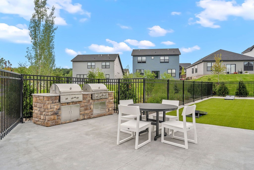 a patio with a table and chairs and a grill
