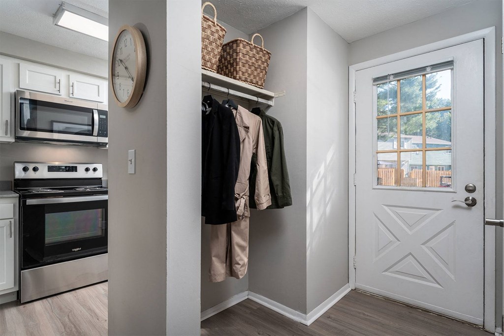 a walk in closet with a door to a kitchen with a microwave and a door