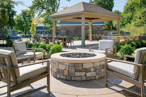 a fire pit with chairs and a gazebo in the middle of a