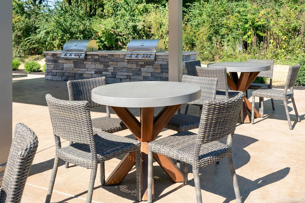 a patio with tables and chairs and a barbecue grill