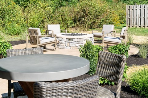 a patio with chairs and tables and a fire pit