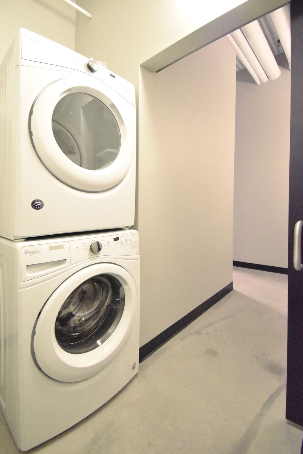 Two white front loading washing machines stacked on top of each other.