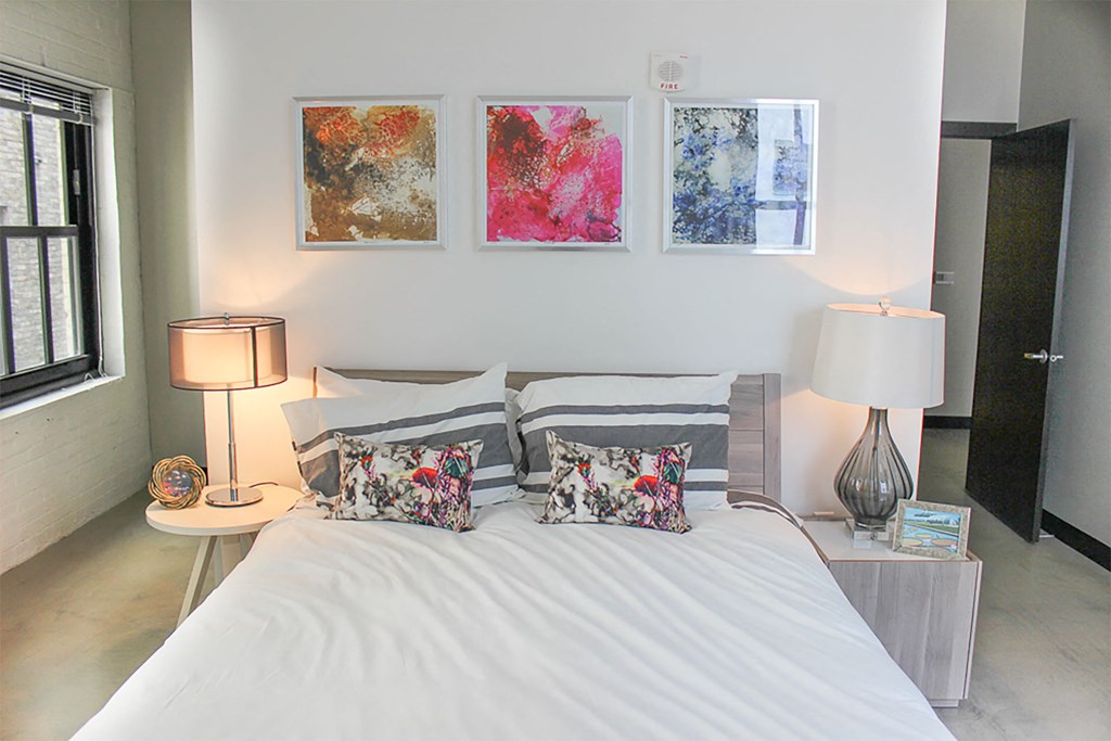 A bedroom with a large bed and two lamps.