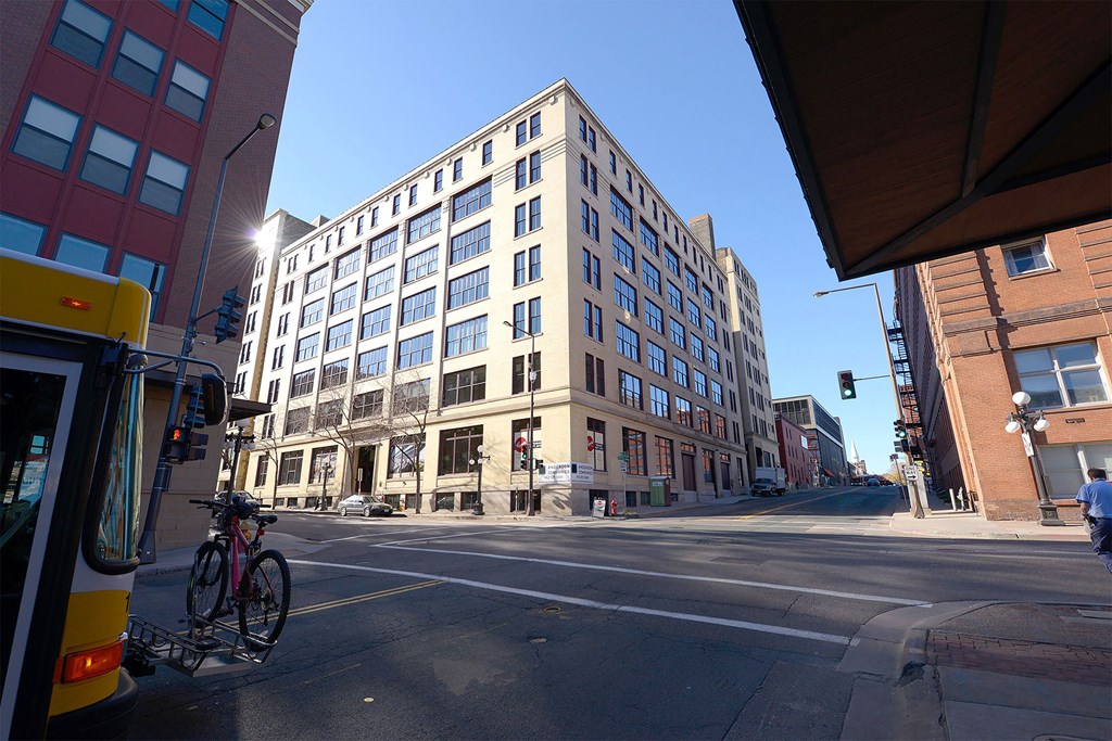 A city street with a bus, a bicycle, and a tall building.