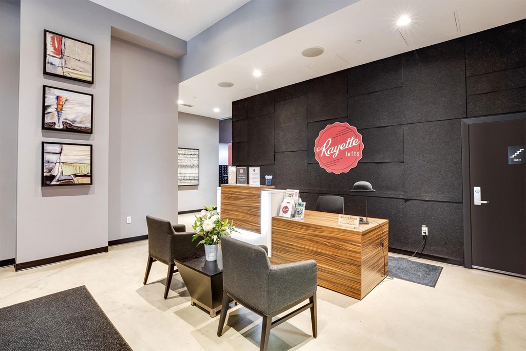 A reception area with a wooden desk and chairs, a potted plant, and pictures on the wall.