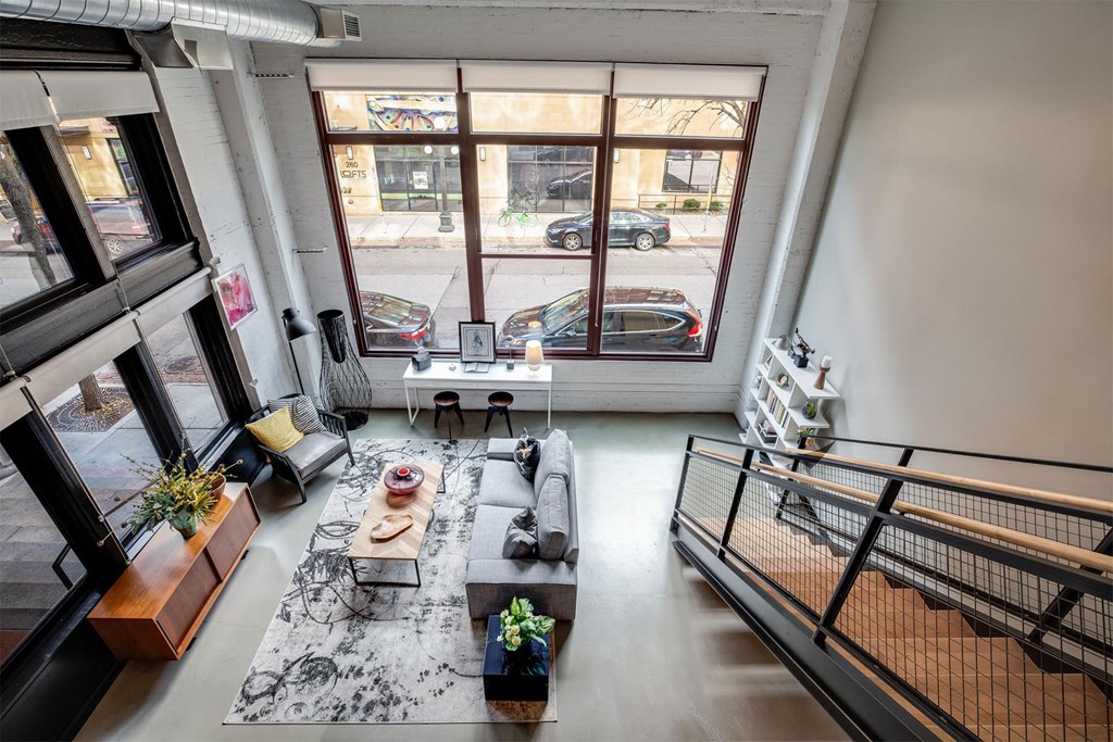 A living room with a black and white rug, a wooden coffee table, and a staircase.