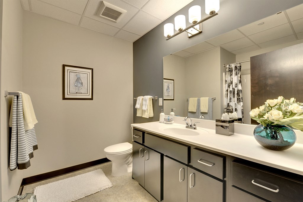 A bathroom with a toilet, sink, and mirror.