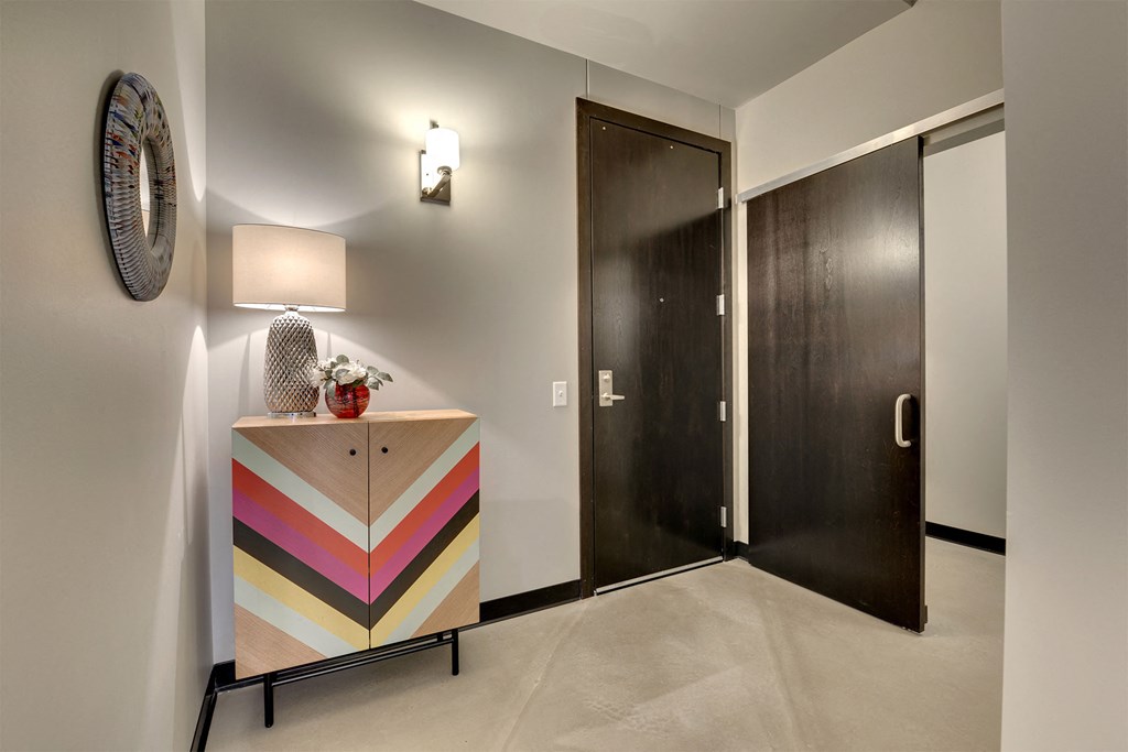 A wooden cabinet with a chevron pattern painted in pastel colors sits in a hallway.