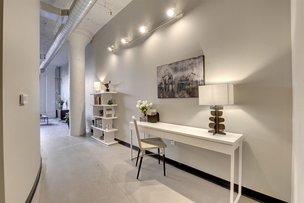 A white desk with a chair and a painting on the wall.