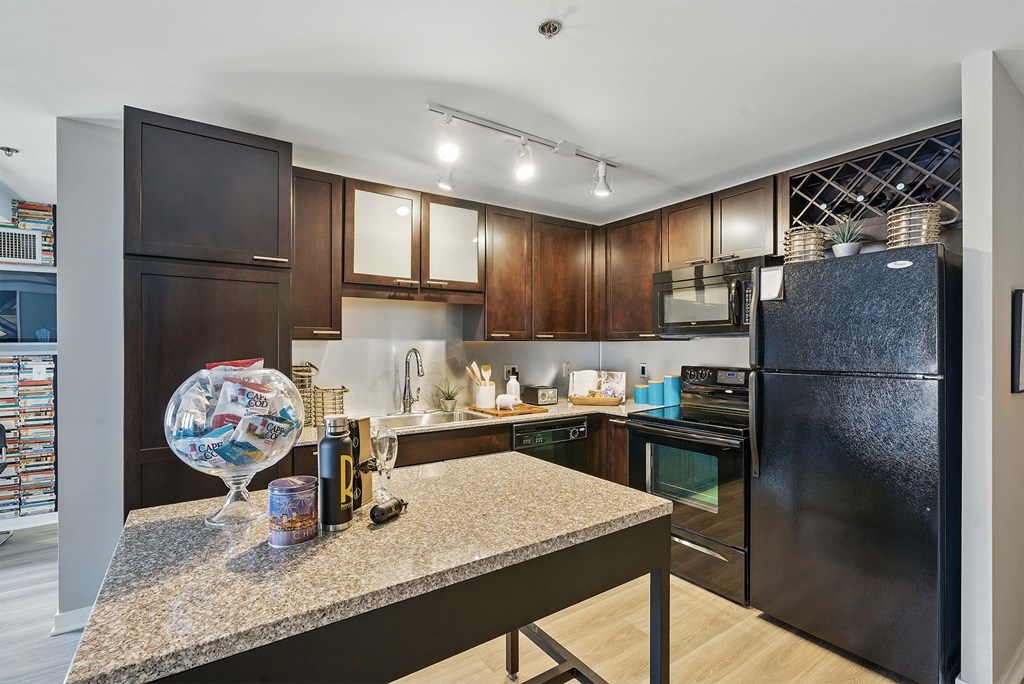 A kitchen with dark wood cabinets and a black refrigerator.