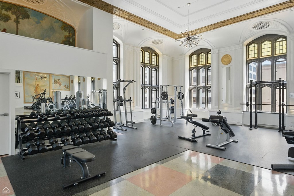 A gym with a variety of equipment including dumbbells, weight machines, and a bench press.