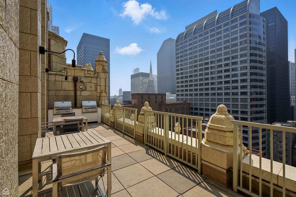 A balcony with a table and chairs overlooks a cityscape.