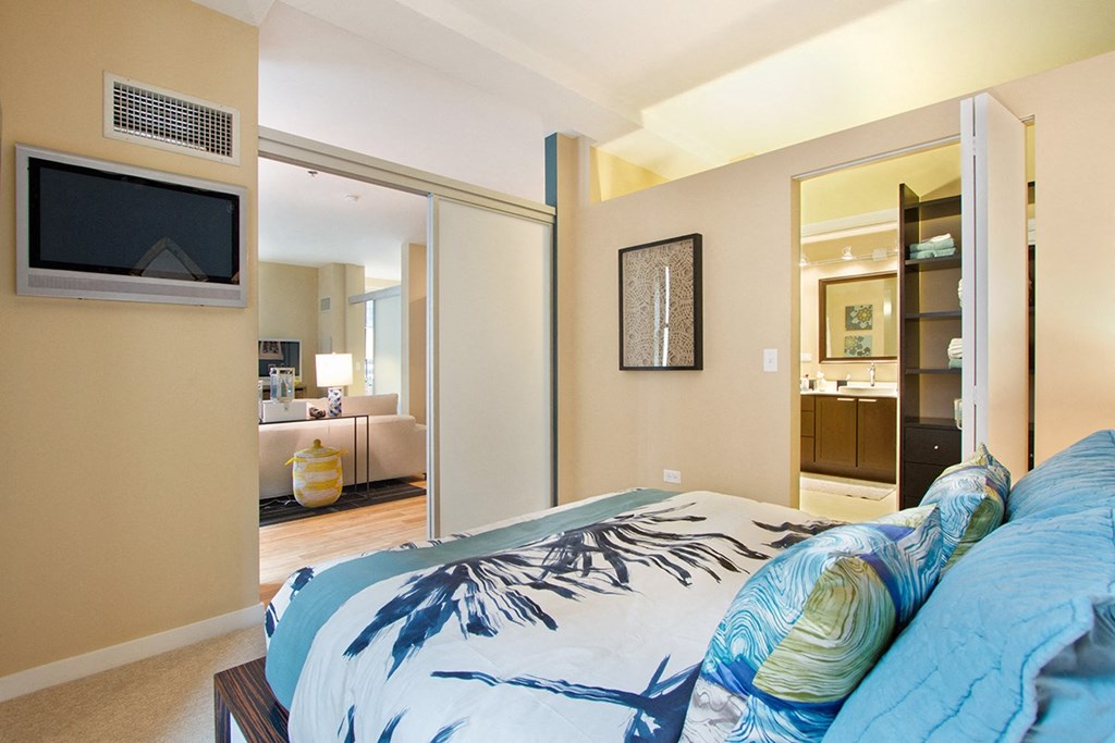 a bedroom with a large bed and a bathroom with a tv