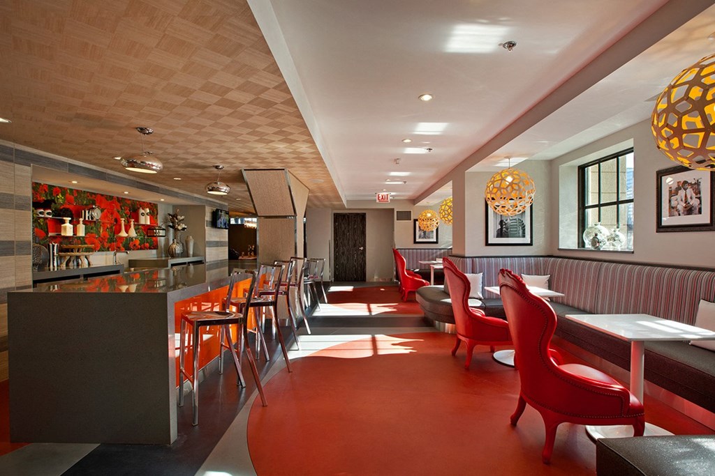 the dining area of a restaurant with red chairs and a bar