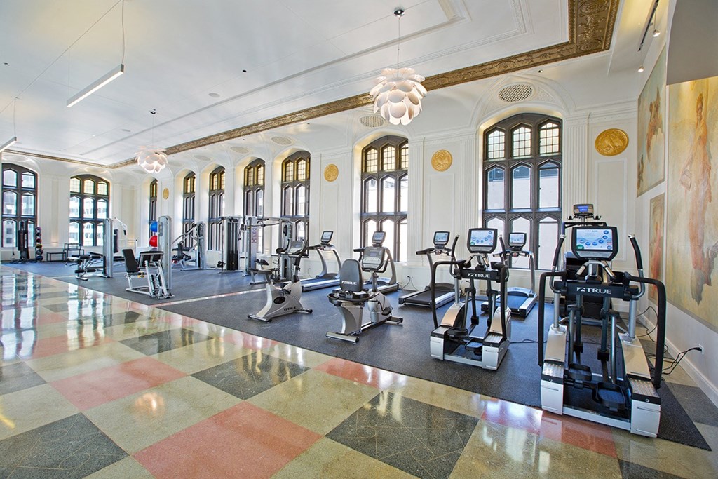 a workout room with treadmills and other exercise equipment in a building with windows