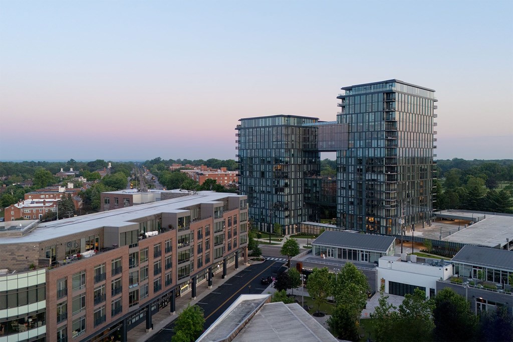 A modern glass building stands next to a row of older buildings.