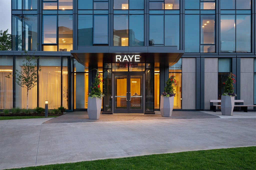 The Raye building is shown at dusk with lights on inside.