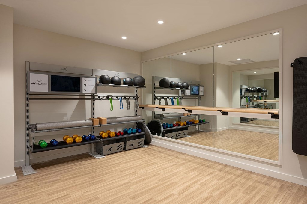 A room with a mirrored wall and a shoe rack with multiple pairs of shoes.
