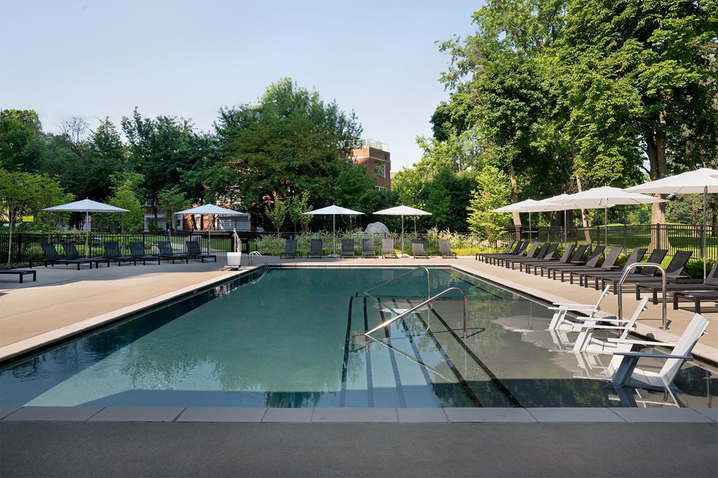 A large outdoor swimming pool surrounded by sun loungers and umbrellas.