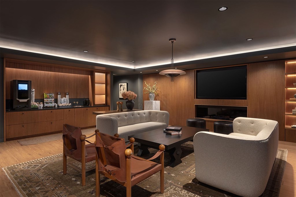 A modern living room with a grey sofa and wooden chairs.