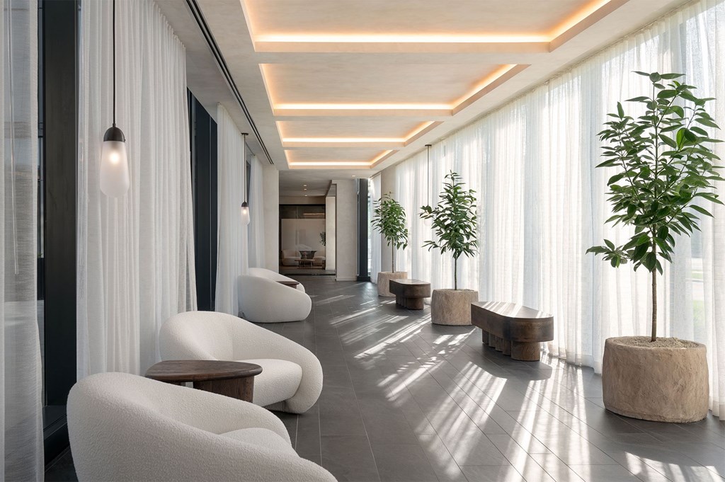 A modern living room with white furniture and plants.