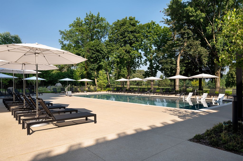 A pool area with sun loungers and umbrellas.
