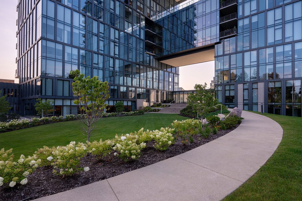 A modern building with glass windows and a landscaped garden in front.