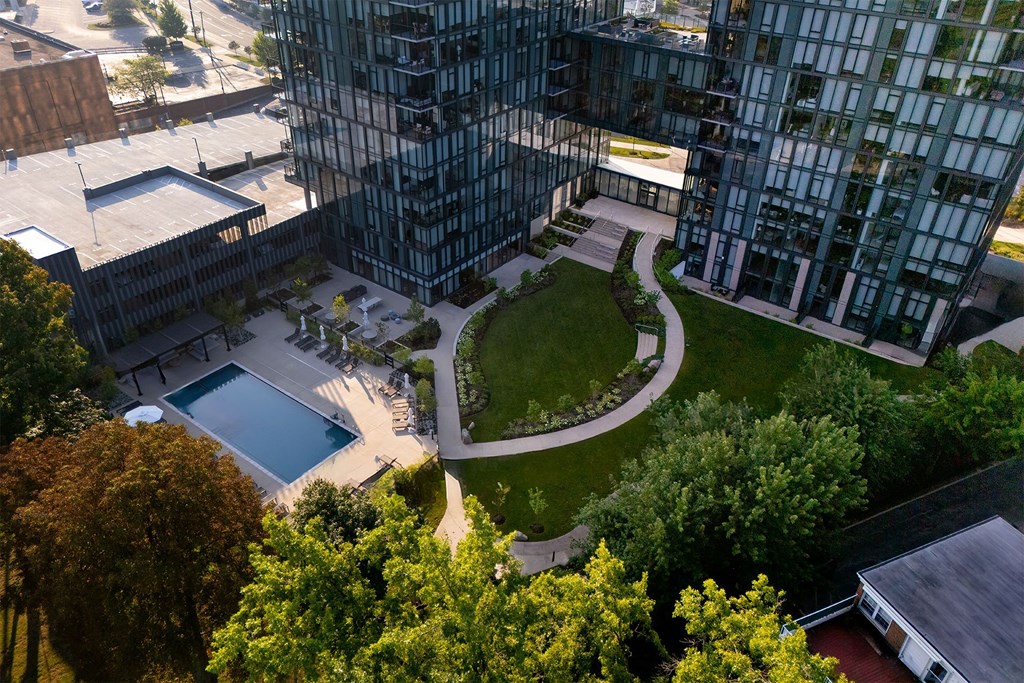 A modern glass building with a pool and a green lawn in front.