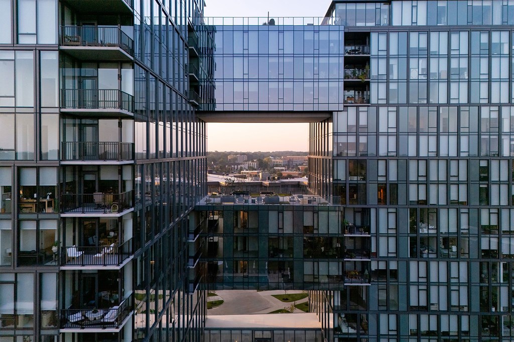 A modern glass building with balconies and a view of the city.
