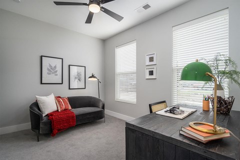 A living room with a black couch and a ceiling fan.